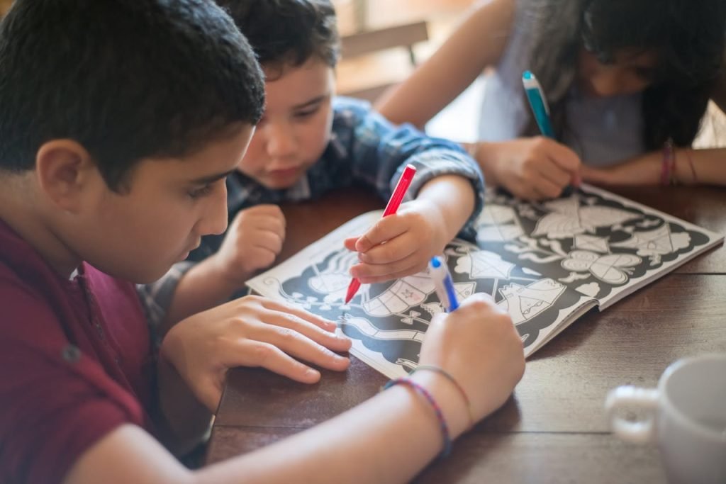 A group of children focused on coloring in an activity book at a wooden table.