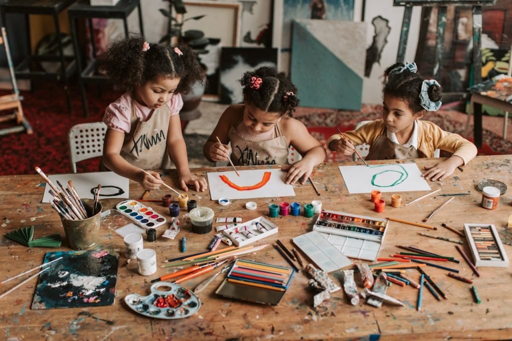 Three young girls engaged in a vibrant painting session at an art studio.